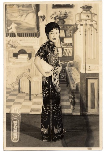 Actress in a sequinned cheongsam holding an ostrich fan /