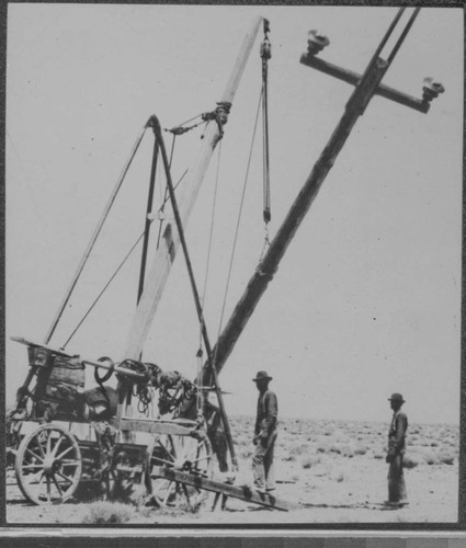 Line crew with horse drawn wagon erecting a transmission pole in the desert with a derrick and gin pole