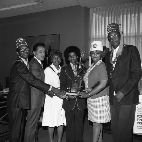 Elbert T. Hudson and Shriners posing with a young man and a trophy, Los Angeles, 1974