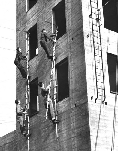Rookie firemen using scaling ladders