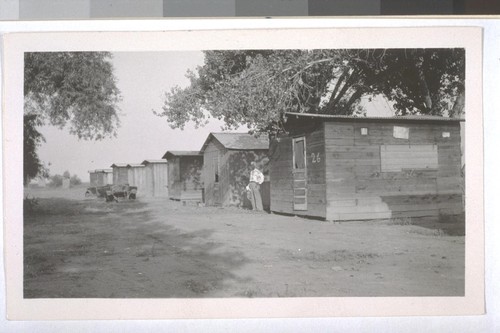 July, 1936, Kern County, Kern Lake District. The typical laborer cabins. The Deputy Health Officer of Kern County is standing near the cabin