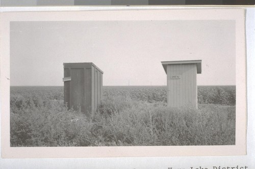 July, 1936, Kern County, Kern Lake District. The old and the new. An old style privy alongside of Public Health Service privy. Both are dirty inside showing no supervised effort to keep clean. Note the weeds in front and the excellent field of growing cotton in the rear