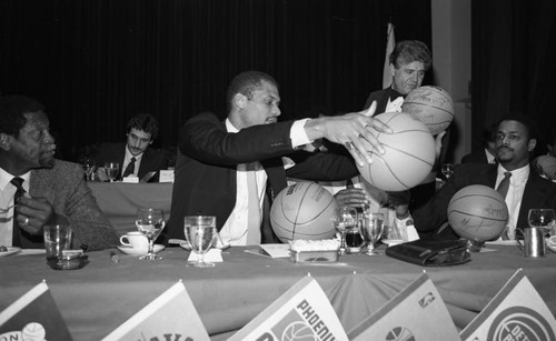 Bill Russell watching Kareem Abdul Jabbar sign basketballs at the NBA All-Star Game dinner, Los Angeles, 1983