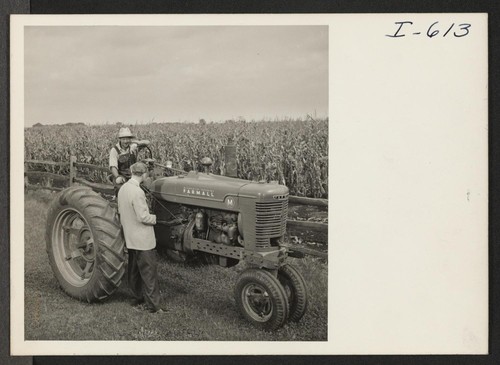 Rokuro Okubo stops his tractor to talk to a Chicago District Office relocation officer, W. W. Lessing (back to camera)