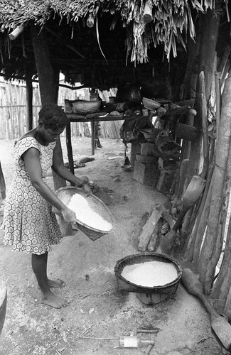 A young lady pours corn meal into a basket, San Basilio de Palenque, 1977