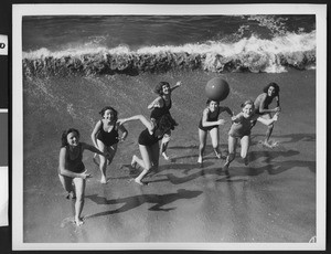 Women wearing bathing suits tossing a ball at a Los Angeles area beach, ca.1930