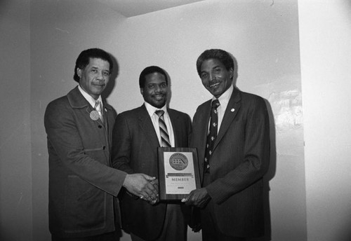 Black Business Association members posing together with a plaque, Los Angeles, 1982