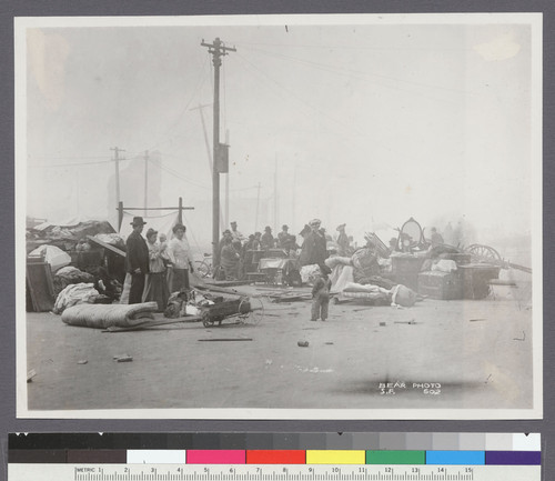 [Street scene of refugees with belongings. Unidentified location.]