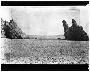 View of Balboa Beach in Corona Del Mar, seen between two rock formations, 1924