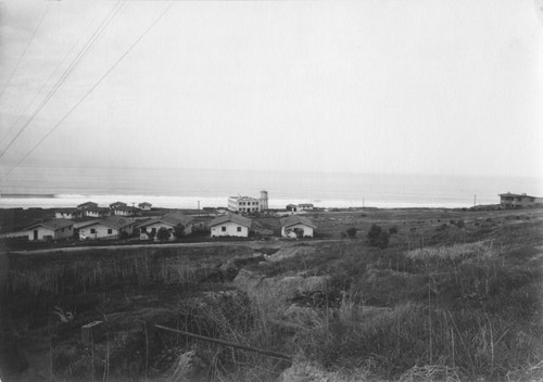 The campus of Scripps Institution for Biological Research, which would later become Scripps Institution of Oceanography. Residential cottages in foreground with the George H. Scripps Memorial Marine Biological Laboratory and adjacent seawater tower. Circa 1914