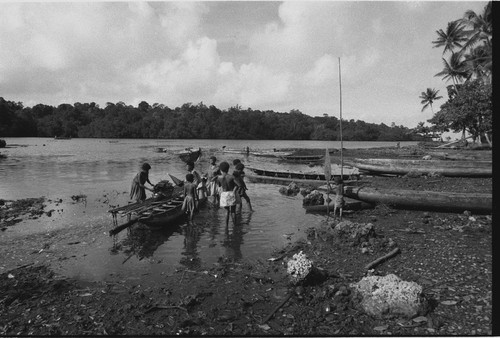 Canoes: women load baskets onto canoe in lagoon