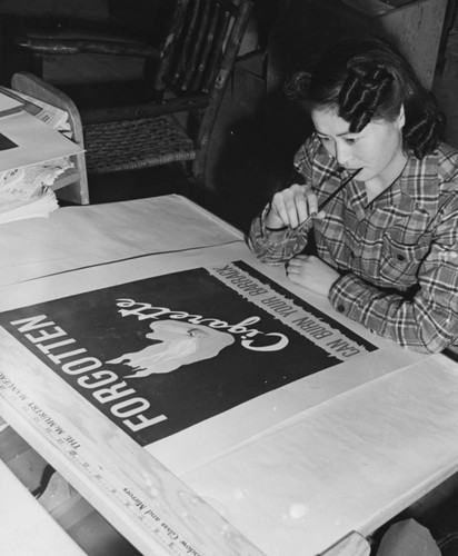 [Young artist completing a poster in poster shop at Heart Mountain incarceration camp]