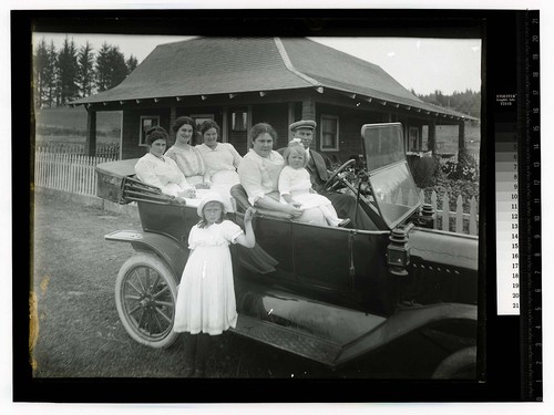 [Seven people posing in and by an automobile]