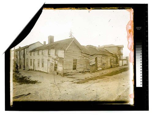 [Three connected wooden buildings, middle one falling down]