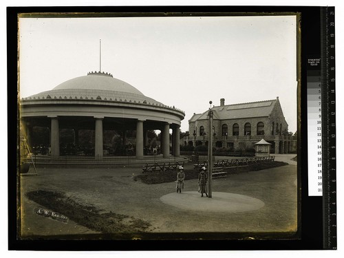 [Two girls pose near a merry-go-round in an urban setting]