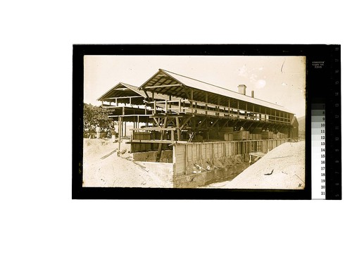 [Workers in large open air shed building]