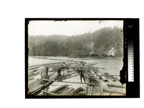 [Two men pose at work in a log pond]