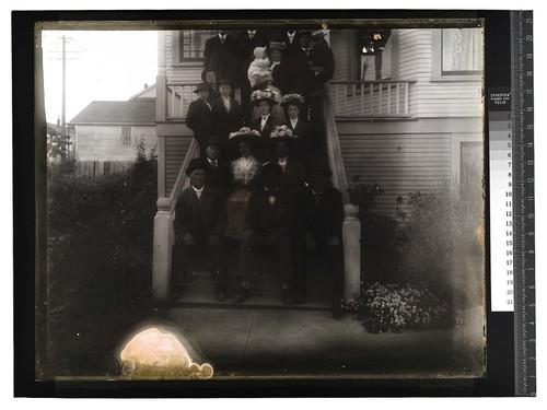 [About twenty people posing on the steps of a house]