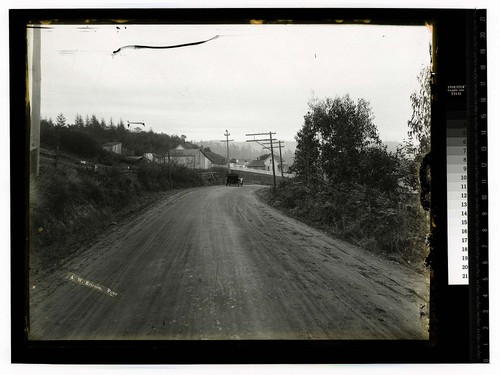 [Auto on dirt road passing barns and a farm house]