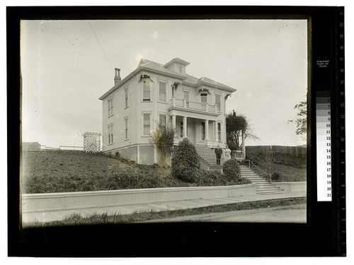 [Couple standing on steps of a large two story house]