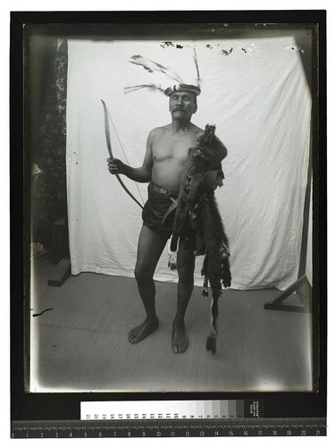 [Portrait of an Indian man with ceremonial headdress standing in front of a drape #2]