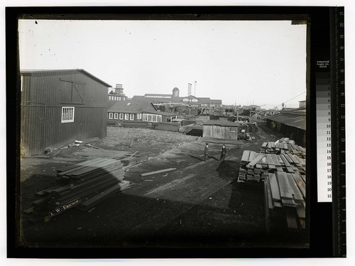 [Two men amidst a large lumber mill]