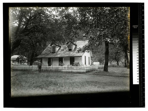 [Man standing in front of fenced house at Hoopa Valley Reservation]