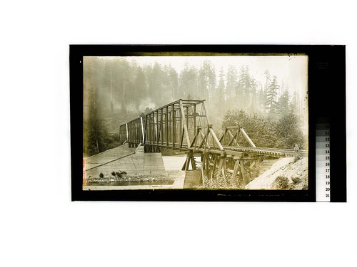 [Young child posing on tracks of a railroad bridge]