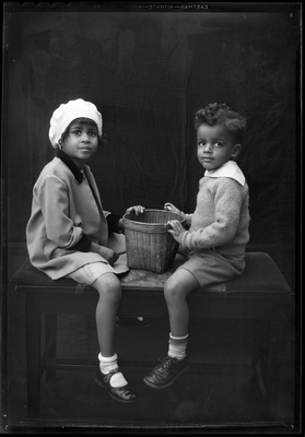 Portrait of boy and girl sitting on bench with wicker basket