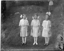 Three girls in white dresses, with large bows in their hair, c. 1912