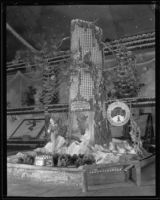 Pat Graham holds oranges and stands with a foot up on the Crest Forest Resort display at the National Orange Show, San Bernardino, 1934