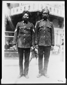 Two old men wearing uniforms on a street corner