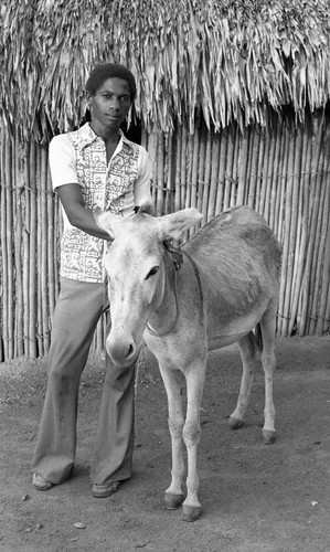 Teenage boy standing next to a mule, San Basilio de Palenque, 1976