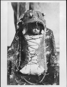 Portrait of a Native American child wrapped in a papoose
