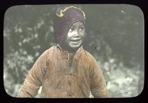 Smiling child wearing a coat and hat, China, ca. 1918-1938