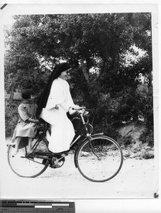 Maryknoll Sister rides a bike at Soule, China