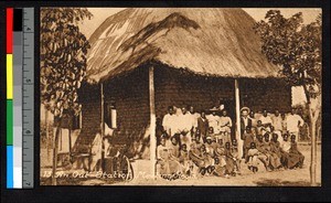 Men and women gathered outside of a thatch-roofed meeting room, Angola, ca.1920-1940