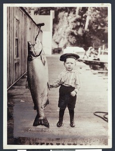 Young boy standing next to a Columbia River salmon, Oregon