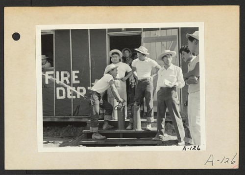 Poston, Ariz.--Evacuee firechief, Tom Nishimura, discusses Army type fire extinguisher with his staff at this War Relocation Authority center. Photographer: Clark, Fred Poston, Arizona
