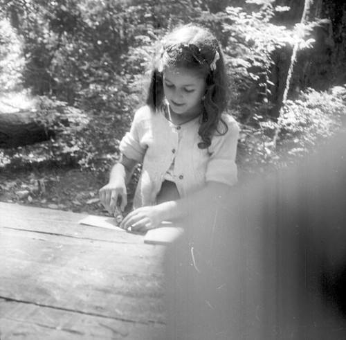 Young girl working at a table in the woods