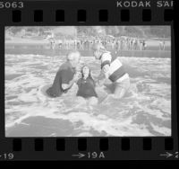 Jack McKee and Rev. Kenn Gulliksen baptizing Diane Hunter in surf at Will Rogers State Beach, Calif., 1976