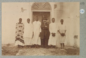 Missionary Schachschneider(?) with 3 African men and 2 African women in front of the door of a European building, ca.1901-1914