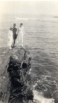 Two women and soldier on rock outcrop above Pacific Ocean