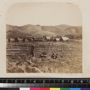 View of forest village with missionary and two indigenous men in foreground, Madagascar, ca.1865-1885