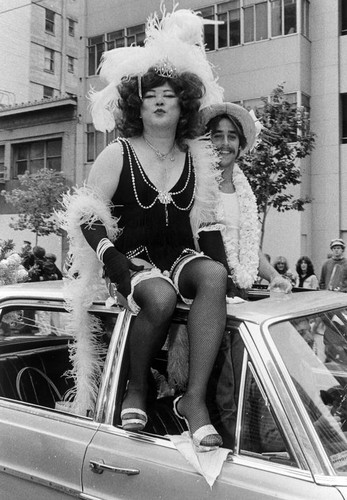 Female impersonator parade participant on top of car float