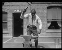 George Godfrey, heavyweight boxer, posing with anvil [outside the KJH Radio studio, Los Angeles(?)], circa 1926-1927