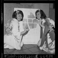 Two Japanese American woman in kimonos giving "o.k." hand sign to map showing redevelopment plan for Los Angeles' Little Tokyo, 1964