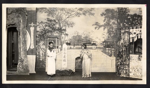 Scholar in spectacles with a woman leaning on a hoe in a garden, staged at the Great Star Theatre /