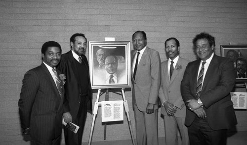 Tom Bradley and others posing with a painting at the California African American Museum, Los Angeles, 1985