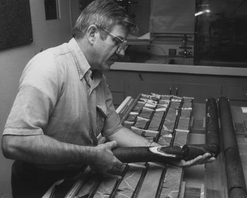 Inspecting basalt in the Core Laboratory aboard the D/V Glomar Challenger (ship), recovered on Leg 88, during the Deep Sea Drilling Project is scientist Anton Interbitzen from the National Science Foundation (NSF). 1982